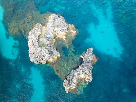 Aerial view of jagged sun kissed rocks rise from the mesmerizing turquoise waters of the Blue Lagoon contrasting beautifully against the deep blue sea Blue lagoon Comino Malta. Aerial view of jagged sun kissed rocks rise from the mesmerizing turquoise waters of the Blue Lagoon contrasting beautifully against the deep blue sea Blue lagoon Comino Malta.