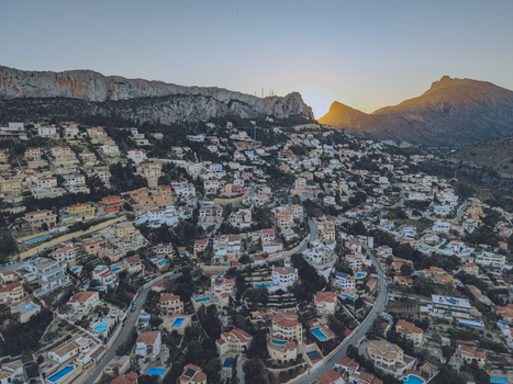Aerial view of residential houses with swimming pools nestled on a hillside at sunset with the rocky Penyal d Ifac mountain in the background in Calp Valencian Community Spain. Aerial view of residential houses with swimming pools nestled on a hillside at sunset with the rocky Penyal d Ifac mountain in the background in Calp Valencian Community Spain.