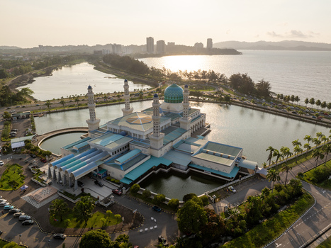 Aerial view of the Kota Kinabalu City Mosque with its blue dome and minarets surrounded by a lagoon at sunset in Kota Kinabalu Sabah Malaysia. Aerial view of the Kota Kinabalu City Mosque with its blue dome and minarets surrounded by a lagoon at sunset in Kota Kinabalu Sabah Malaysia.