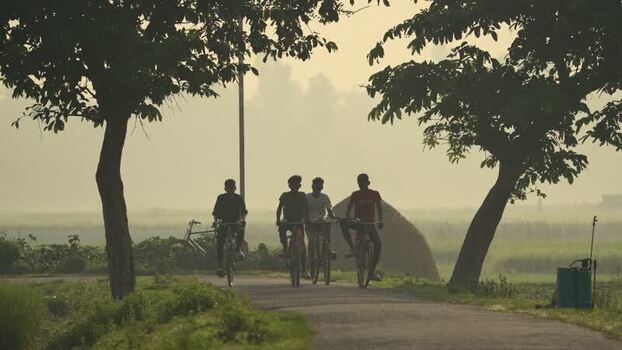 View of young men cycling on a rural road in Bogura Bangladesh.