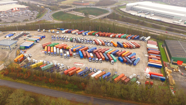 Aerial view of a large truck parking lot filled with colorful shipping containers and semi trucks in Southampton England United Kingdom.