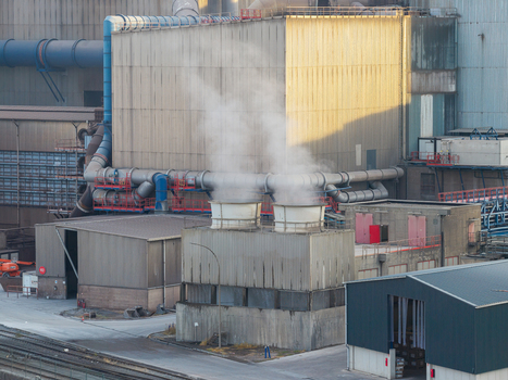 Aerial view of the industrial facilities at Haven Genk featuring cooling towers emitting steam complex piping systems and warehouse structures in Genk Vlaanderen Belgium.