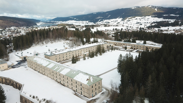 Aerial view of Le Fort des Rousses with its historic stone buildings and snow covered courtyards surrounded by dense evergreen forests and mountains in Les Rousses Bourgogne Franche Com France.
