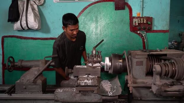 View of a worker operating a lathe machine in a workshop Bangladesh.