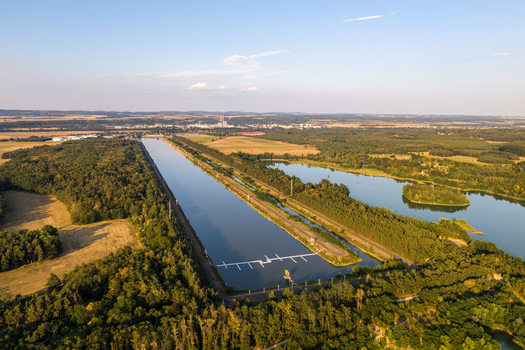 Aerial view of Labe Arena Racice surrounded by lush green forests and calm water under a clear summer sky in Racice Ustecky kraj Czechia. Aerial view of Labe Arena Racice surrounded by lush green forests and calm water under a clear summer sky in Racice Ustecky kraj Czechia.