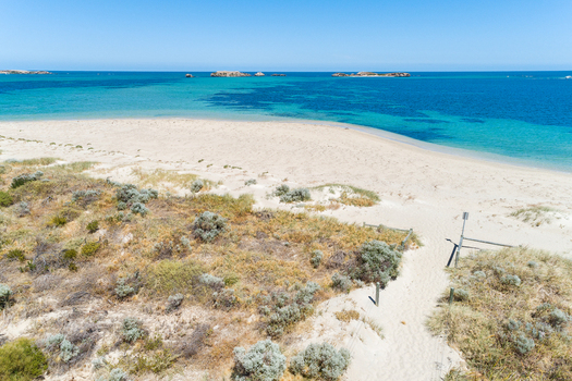 Aerial view of a pristine sandy beach with turquoise waters coastal dunes and native vegetation under a clear blue sky in Perth Western Australia Australia. Aerial view of a pristine sandy beach with turquoise waters coastal dunes and native vegetation under a clear blue sky in Perth Western Australia Australia.