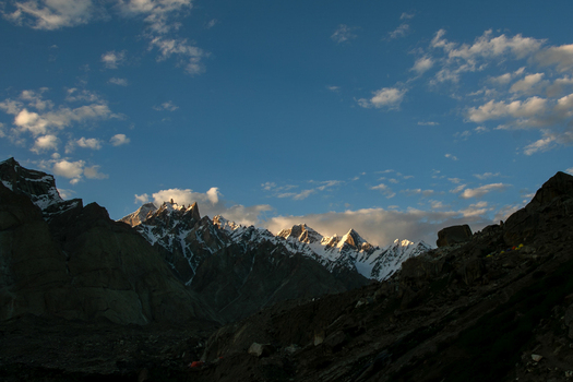 View of Goro II campsite with snow capped peaks of the Karakoram range illuminated by golden light under a blue sky in k2 basecamp trek Gilgit Pakistan. View of Goro II campsite with snow capped peaks of the Karakoram range illuminated by golden light under a blue sky in k2 basecamp trek Gilgit Pakistan.