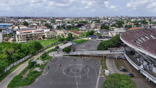 Aerial view of National Stadium Surulere Lagos with people playing on an outdoor court surrounding urban buildings and lush green trees Lagos Lagos Nigeria. Aerial view of National Stadium Surulere Lagos with people playing on an outdoor court surrounding urban buildings and lush green trees Lagos Lagos Nigeria.