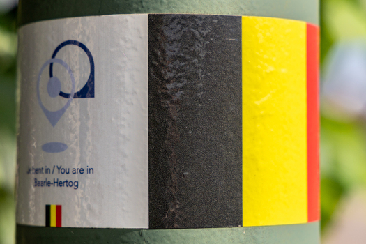 View of a sticker on a pole indicating the location of Baarle Hertog featuring the Belgian flag in Baarle Hertog Flanders Belgium.