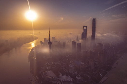 Aerial view of the Lujiazui financial district skyscrapers shrouded in thick morning fog during sunrise over the Huangpu River in Shanghai Shanghai China.