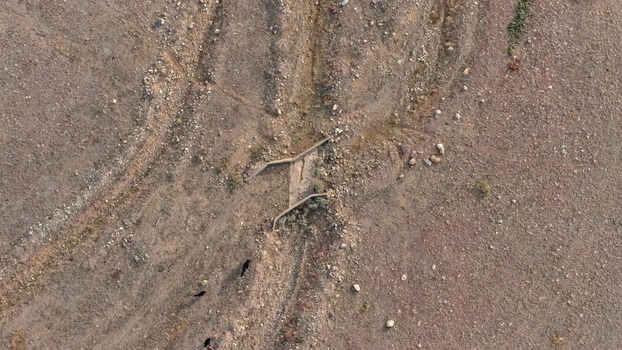Aerial view of a small concrete drainage structure set within a dry rocky desert landscape with sparse vegetation and scattered dark rocks in Golden Colorado United States.