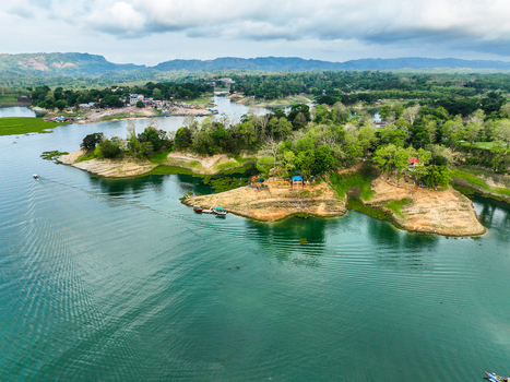 Rangamati Hill District Bangladesh 18 May 2024 Aerial view of Kaptai Lake with lush green islands clear turquoise water small boats and surrounding hills under a cloudy sky.