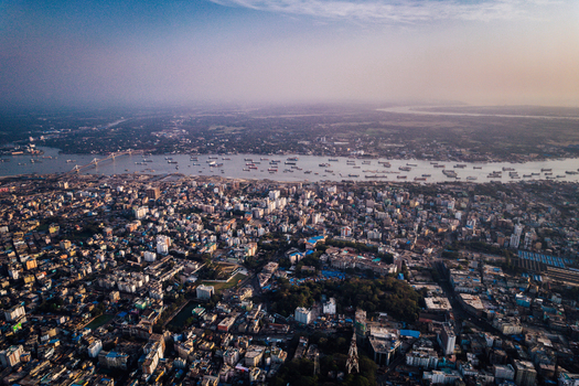 Chattogram Bangladesh 25 February 2022 Aerial view of the dense urban landscape of Chattogram featuring the Karnaphuli River with cargo ships a bridge and city buildings.
