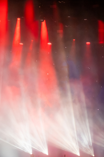View of stage lighting with vibrant red beams cutting through thick haze at a concert in Nyon Vaud Switzerland.