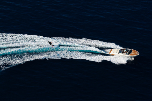 Aerial view of a person wakeboarding behind a motorboat on the deep blue sea near Le Trayas Saint Raphael Provence Alpes Cote d Azur France. Aerial view of a person wakeboarding behind a motorboat on the deep blue sea near Le Trayas Saint Raphael Provence Alpes Cote d Azur France.