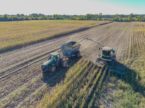 Green Bay Wisconsin United States 25 September 2026 Aerial view of a forage harvester chopping corn for silage into a trailer pulled by a tractor in a field.