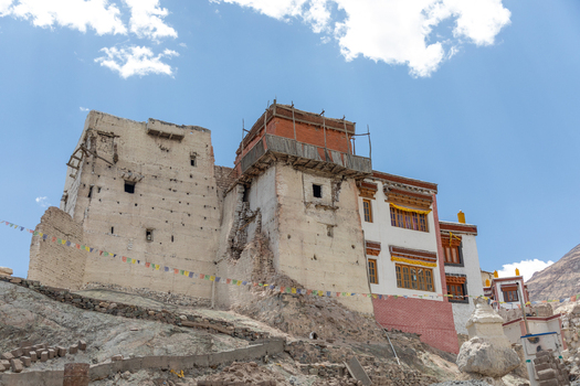 View of the historic Charasa Gonpa monastery featuring traditional white and red walls wooden balconies and colorful prayer flags against a blue sky in Charasa Ladakh India.
