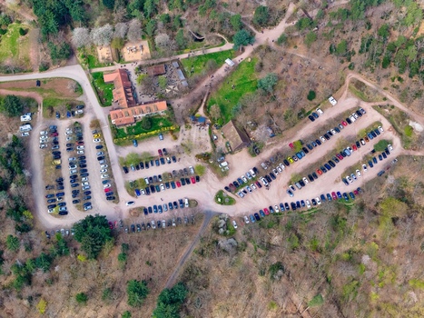 Aerial view of cars neatly arranged in parking lots near buildings nestled amid the green and brown hues of the surrounding forest Kintzheim Grand Est France.