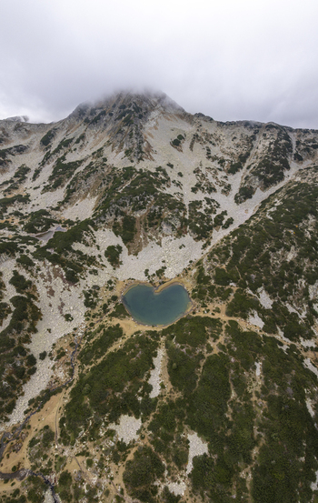 Aerial view of Muratovo Lake in Pirin National Park featuring its distinctive heart shape surrounded by rugged rocky slopes and alpine vegetation in Blagoevgrad Province Bulgaria. Aerial view of Muratovo Lake in Pirin National Park featuring its distinctive heart shape surrounded by rugged rocky slopes and alpine vegetation in Blagoevgrad Province Bulgaria.