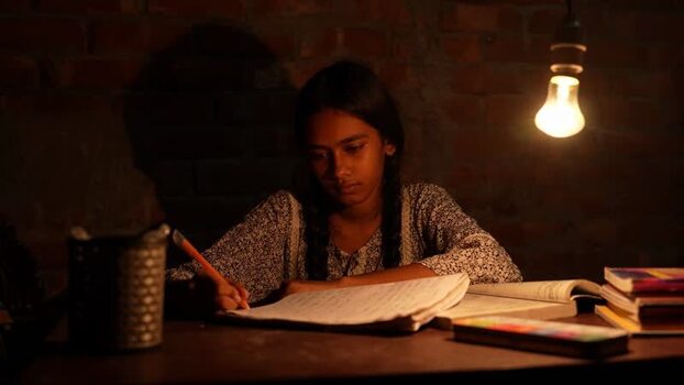 View of a young girl studying under a light bulb Bangladesh.