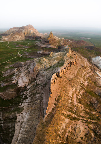 Aerial view of Airakty mountains with dramatic rock formations winding dirt paths and green grassy plains in Shetpe Mangystau Region Kazakhstan.