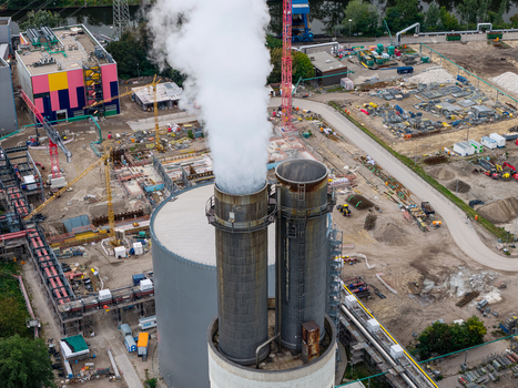 Aerial view of Heizkraftwerk Reuter West power plant with steam rising from chimneys surrounded by industrial infrastructure construction cranes and pipes in Berlin Berlin Germany.