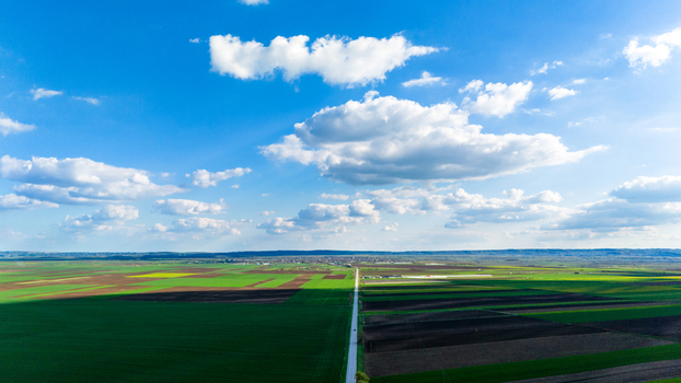 Aerial view of patchwork fields in vibrant greens and browns under a vast sky with fluffy clouds Kovilj Vojvodina Serbia. Aerial view of patchwork fields in vibrant greens and browns under a vast sky with fluffy clouds Kovilj Vojvodina Serbia.