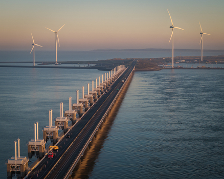 Aerial view of the Oosterscheldekering storm surge barrier and wind turbines at sunset in Vrouwenpolder Zeeland Netherlands.