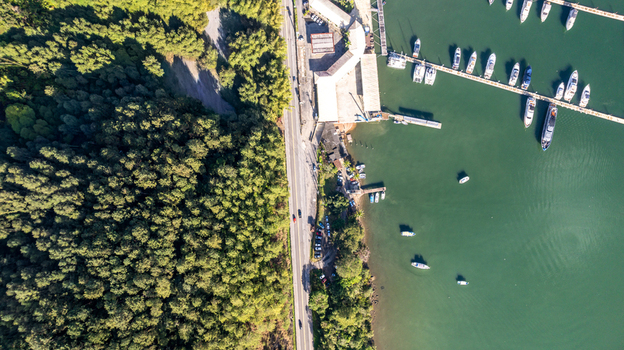 Aerial view of the marina with numerous boats docked along the pier bordered by a lush forest and a coastal road in Angra dos Reis State of Rio de Janeiro Brazil.