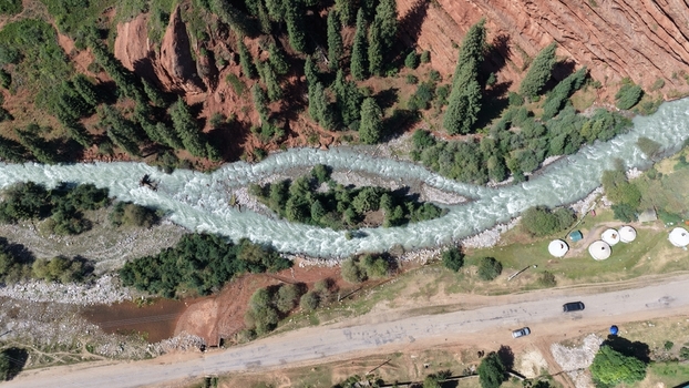 Aerial view of the Jety Oguz river flowing through a valley with red rock cliffs pine forests a road with cars and traditional yurts in Jety Oguz Issyk Kul Region Kyrgyzstan. Aerial view of the Jety Oguz river flowing through a valley with red rock cliffs pine forests a road with cars and traditional yurts in Jety Oguz Issyk Kul Region Kyrgyzstan.