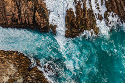 Aerial view of the rugged coastline and turquoise ocean waves crashing against the granite rock formations at Canal Rocks Bridge in Yallingup Western Australia Australia.