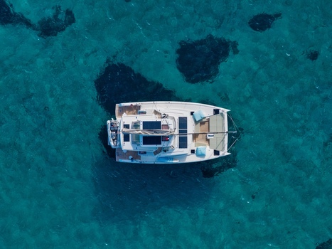 Aerial view of a white catamaran anchored in the clear turquoise waters off the coast of Ile Sainte Marguerite in Cannes Provence Alpes Cote d Azur France. Aerial view of a white catamaran anchored in the clear turquoise waters off the coast of Ile Sainte Marguerite in Cannes Provence Alpes Cote d Azur France.