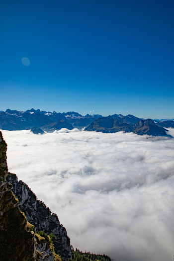 Aerial view of the Swiss Alps rising above a thick blanket of clouds under a clear blue sky in Airolo Ticino Switzerland. Aerial view of the Swiss Alps rising above a thick blanket of clouds under a clear blue sky in Airolo Ticino Switzerland.