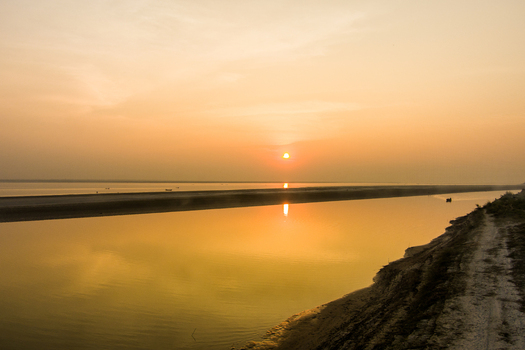 Aerial view of the Padma River at sunset with calm water reflecting the golden light and sandy riverbanks in Rajshahi Rajshahi Division Bangladesh.