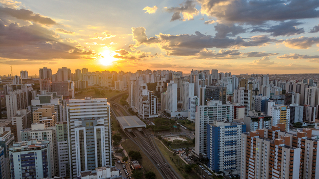 Brasilia Brazil 12 September 2026 Aerial view of the modern skyline of Brasilia at sunset featuring high rise residential buildings railway tracks and a vibrant golden sky.