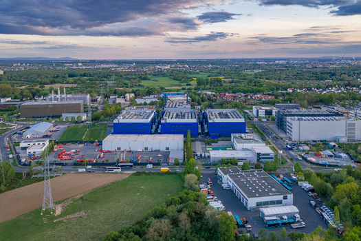 Aerial view of the Digital Realty Frankfurt FRA30 data center complex with modern industrial buildings and green fields under an evening sky in Frankfurt am Main Hessen Germany. Aerial view of the Digital Realty Frankfurt FRA30 data center complex with modern industrial buildings and green fields under an evening sky in Frankfurt am Main Hessen Germany.