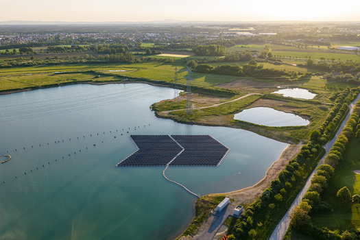 Aerial view of floating solar panels on a lake with power lines and green fields in Bensheim Hessen Germany. Aerial view of floating solar panels on a lake with power lines and green fields in Bensheim Hessen Germany.