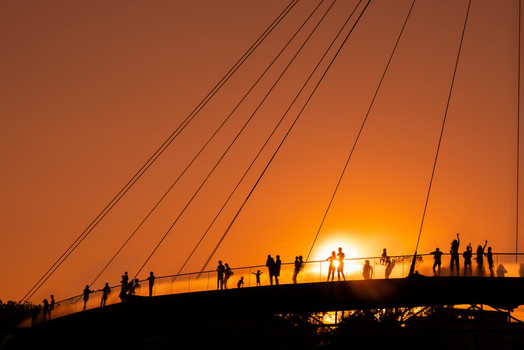 View of silhouettes of people standing on a modern pedestrian bridge during a vibrant sunset in Bucharest Romania. View of silhouettes of people standing on a modern pedestrian bridge during a vibrant sunset in Bucharest Romania.