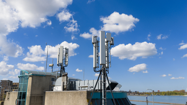 Aerial view of telecommunication antennas and cellular towers on a building rooftop under a blue sky with white clouds Amsterdam North Holland Netherlands. Aerial view of telecommunication antennas and cellular towers on a building rooftop under a blue sky with white clouds Amsterdam North Holland Netherlands.