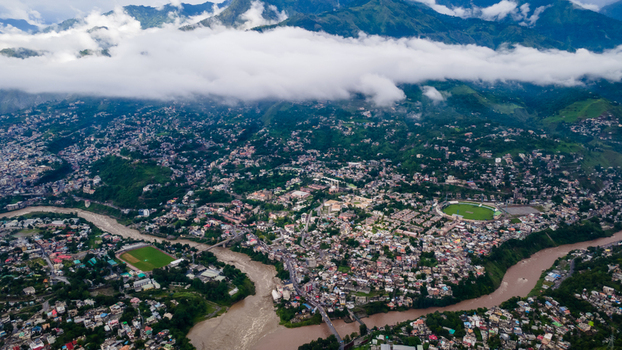 Aerial view of the city nestled in a valley at the confluence of rivers with lush green mountains and low clouds Muzaffarabad Azad Kashmir Pakistan. Aerial view of the city nestled in a valley at the confluence of rivers with lush green mountains and low clouds Muzaffarabad Azad Kashmir Pakistan.