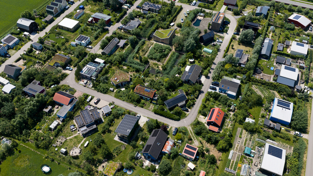 Aerial view of Ecodorp Bolderburen featuring sustainable modern houses with green roofs and solar panels surrounded by lush gardens and winding roads in Almere Flevoland Netherlands. Aerial view of Ecodorp Bolderburen featuring sustainable modern houses with green roofs and solar panels surrounded by lush gardens and winding roads in Almere Flevoland Netherlands.