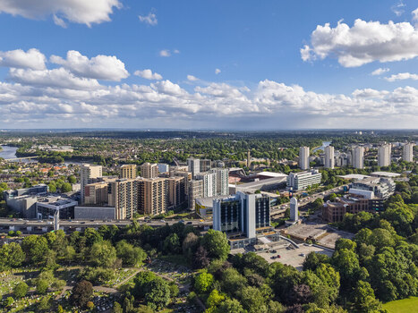 Aerial view of modern residential apartment blocks lush green trees and the River Thames winding through the town in Brentford England United Kingdom. Aerial view of modern residential apartment blocks lush green trees and the River Thames winding through the town in Brentford England United Kingdom.
