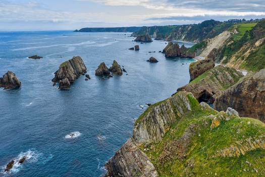 Aerial view of Silence Beach Viewpoint with dramatic sea stacks and rugged cliffs along the green coastline in Cudillero Asturias Spain.