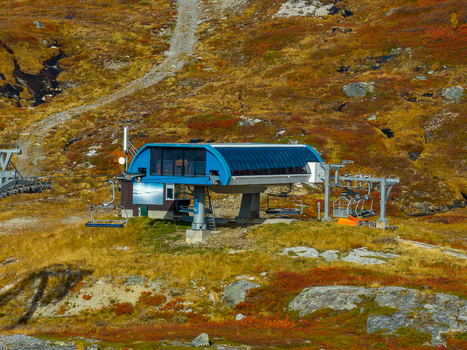 Aerial view of a ski lift station with chairlift chairs on a mountain slope with autumn vegetation in Bjorli Innlandet Norway. Aerial view of a ski lift station with chairlift chairs on a mountain slope with autumn vegetation in Bjorli Innlandet Norway.