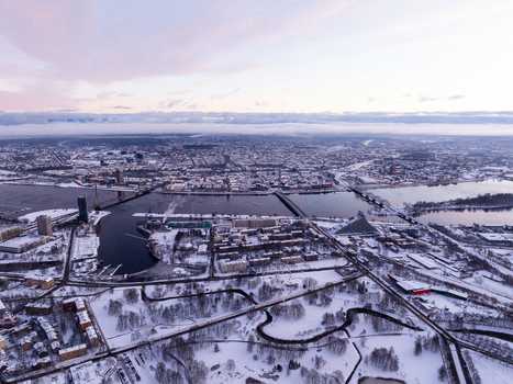 Aerial view of the snow covered cityscape of Riga featuring the Daugava River bridges and the National Library of Latvia under a soft winter sky Riga Latvia.