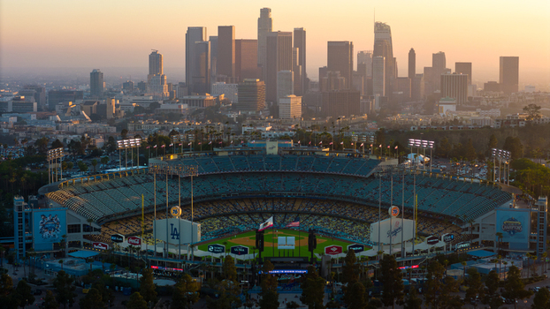 Aerial view of Dodger Stadium basking in the soft glow of the setting sun with the towering skyline silhouetted against the pastel sky Los Angeles California United States. Aerial view of Dodger Stadium basking in the soft glow of the setting sun with the towering skyline silhouetted against the pastel sky Los Angeles California United States.