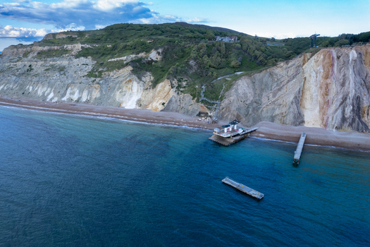 Aerial view of the colorful sandstone cliffs of Alum Bay with a pier and clear blue water Isle of Wight United Kingdom. Aerial view of the colorful sandstone cliffs of Alum Bay with a pier and clear blue water Isle of Wight United Kingdom.