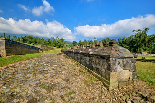 View of the ancient stone walls and cobblestone path at Situs Liyangan archaeological site surrounded by lush greenery and hills in Temanggung Central Java Indonesia.