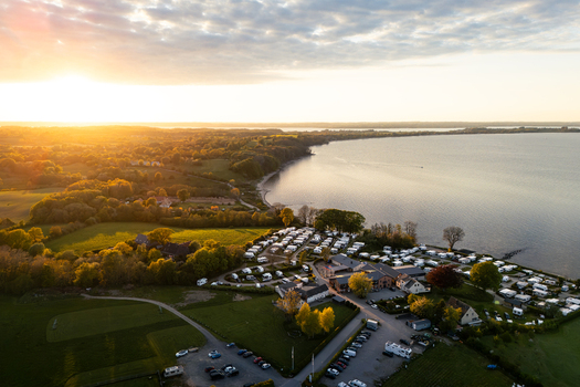 Aerial view of Bockholmwik campsite and the Flensburg Fjord at sunset with parked caravans and lush green fields in Munkbrarup Schleswig Holstein Germany. Aerial view of Bockholmwik campsite and the Flensburg Fjord at sunset with parked caravans and lush green fields in Munkbrarup Schleswig Holstein Germany.