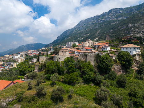Aerial view of the historic Kruje Castle and old town nestled on a lush hillside against the backdrop of rugged mountains in Kruje Durres County Albania.